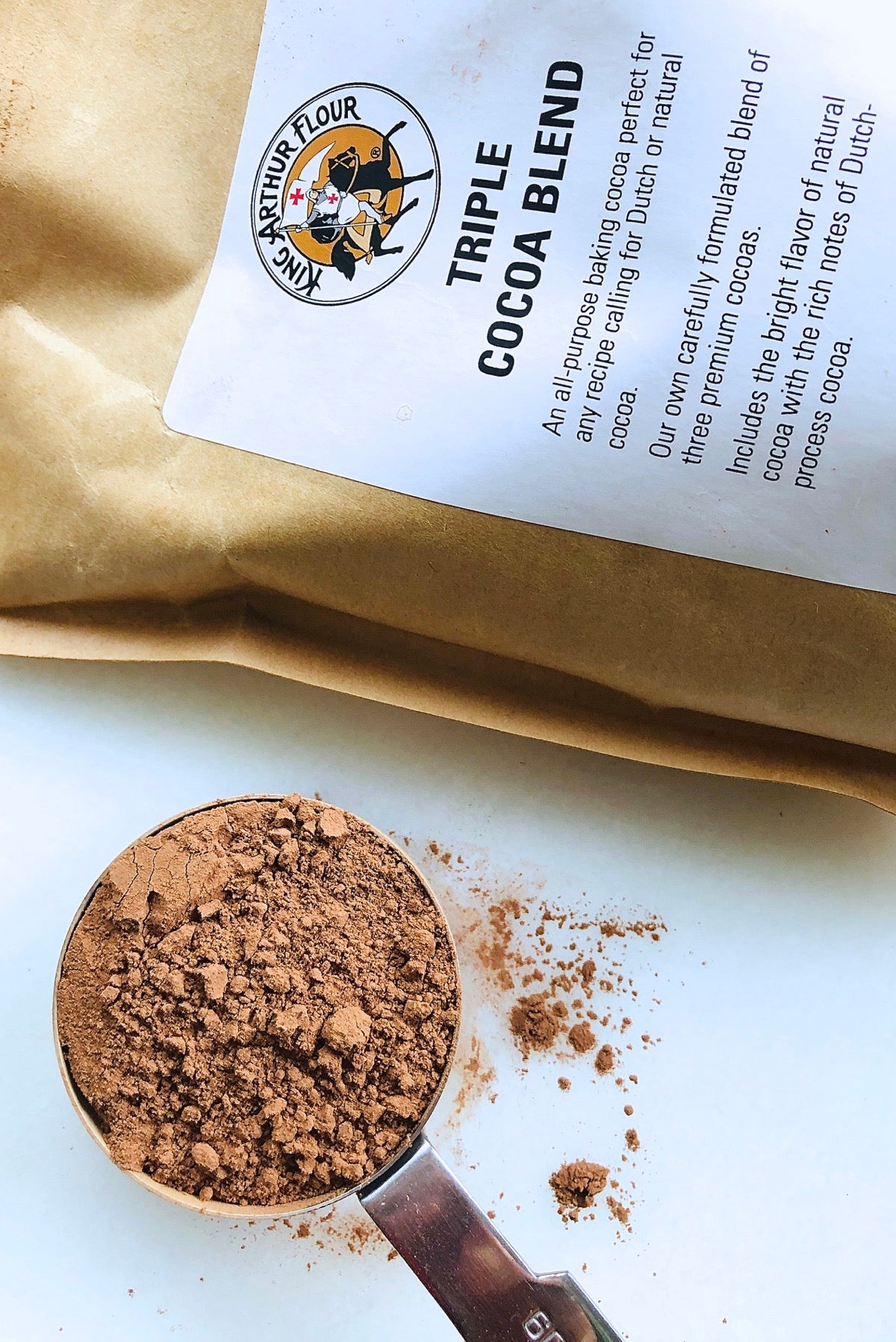 Bag of Triple Cocoa Blend and 1/4-cup measure heaped with cocoa.